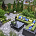 A beautiful small, urban backyard garden featuring a tumbled paver patio, flagstone stepping stones, and a variety of trees, shrubs and perennials add colour and year round interest.