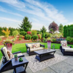 Impressive backyard landscape design. Cozy patio area with settees and table